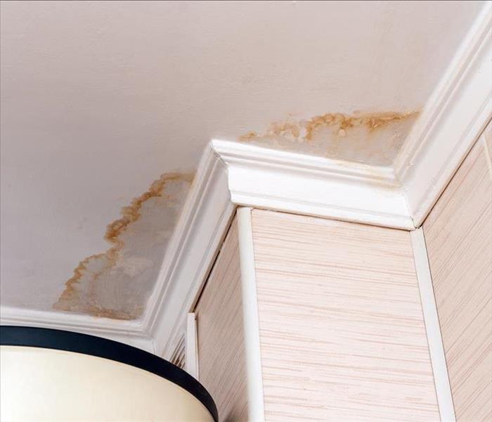 The ceiling of a hotel room has visible discoloration and damage from a leak. 
